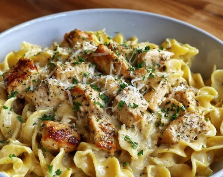 Plate of buttered noodles with chicken topped with herbs and spices