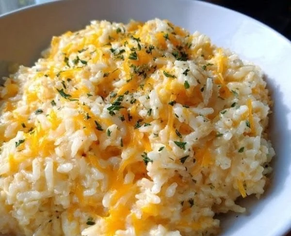 Bowl of cheesy rice topped with cheese and herbs for a delicious meal