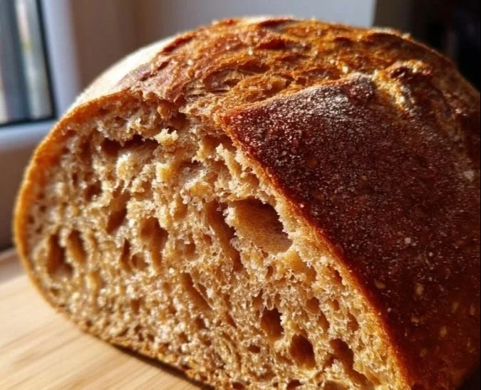 Freshly baked honey wheat bread sliced on a wooden cutting board