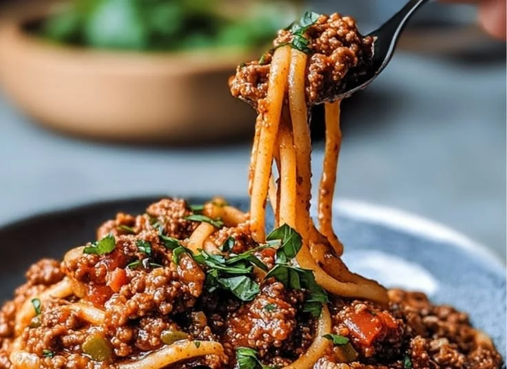 A hearty bowl of Lentil Bolognese served with pasta and fresh herbs.