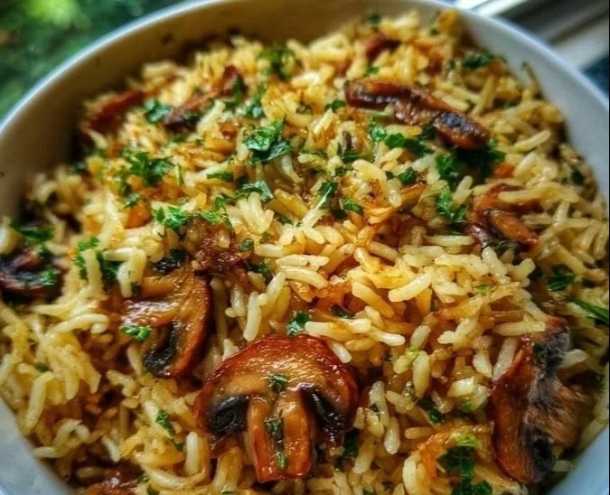 Bowl of flavorful mushroom rice pilaf garnished with herbs