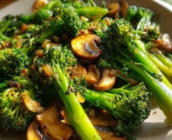 Plate of sautéed mushrooms and broccoli garnished with herbs