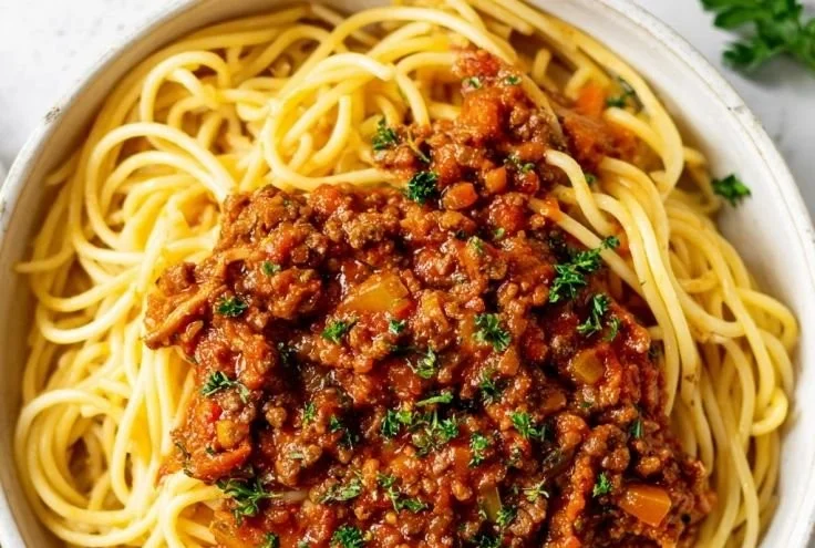 A bowl of hearty Vegetarian Bolognese sauce with fresh ingredients and herbs.