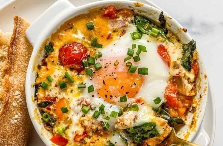 Dish of baked feta eggs garnished with herbs and served in a rustic bowl.