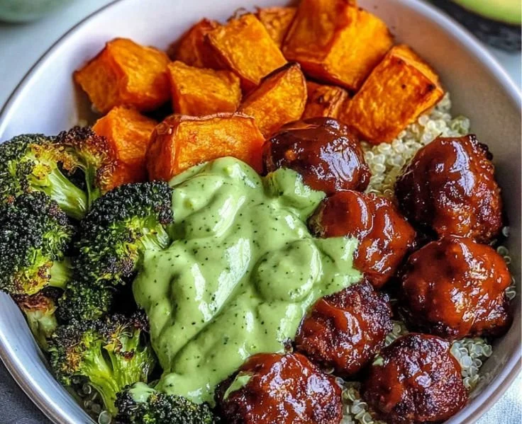 Barbecue meatball bowls garnished with avocado goddess sauce in a colorful dish.