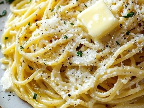 Buttery garlic noodles topped with grated Parmesan cheese in a bowl.