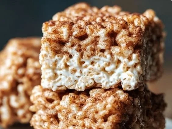 Churro Rice Krispie Treats arranged on a plate, dusted with cinnamon and sugar.