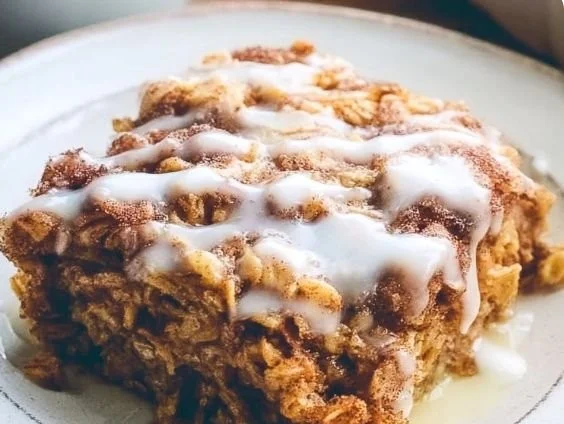 Delicious cinnamon roll baked oatmeal topped with icing and cinnamon.