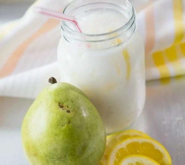 Creamy pear lemonade in a glass with lemon slices and mint leaves