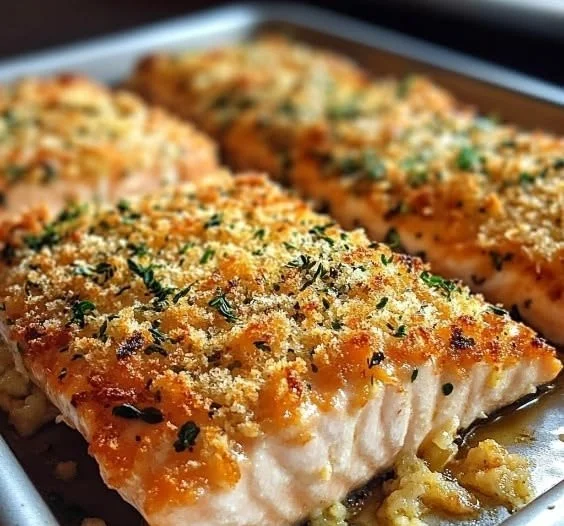 Crispy Parmesan Salmon bake dish served on a white plate with herbs and lemon slices.