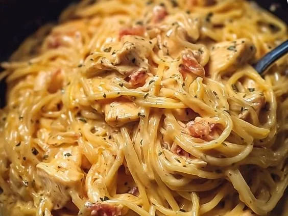 Delicious crockpot cheesy chicken spaghetti in a bowl garnished with herbs.