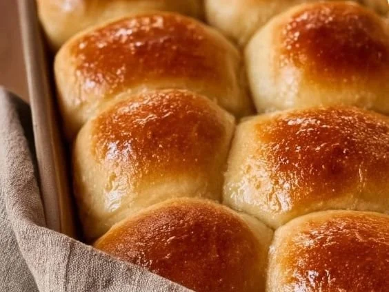 Freshly baked dinner rolls made from sourdough discard on a wooden table.