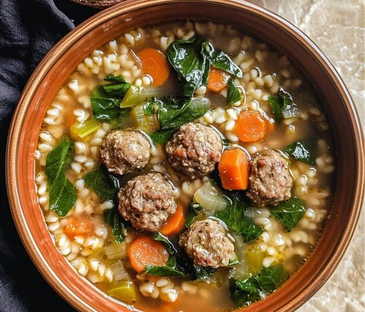 A bowl of homemade Italian Wedding Soup with meatballs and greens.