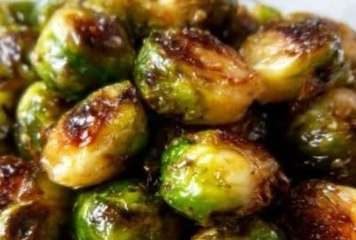 Maple roasted Brussels sprouts served in a bowl, garnished with herbs.