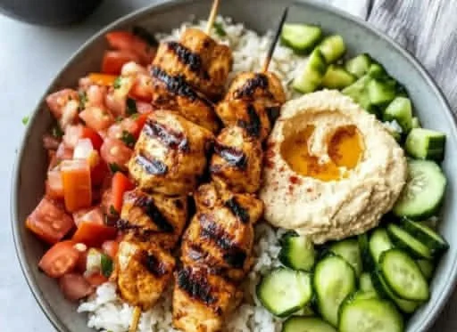 Mediterranean Rice Bowl with Grilled Chicken Tawook Skewers on a plate