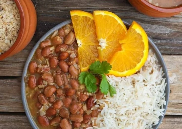 A bowl of protein-packed vegan Brazilian rice and beans garnished with herbs.