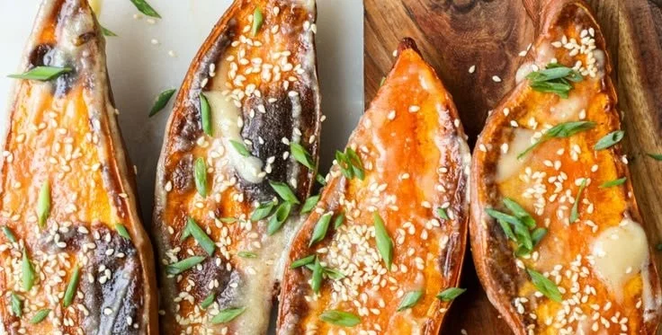 Savory miso butter roasted sweet potatoes garnished with herbs.