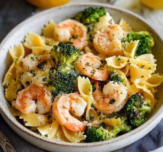 Shrimp and broccoli farfalle pasta dish garnished with fresh herbs