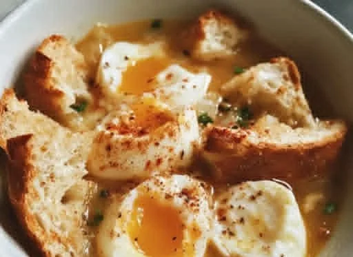 Bowl of Spanish Garlic Soup garnished with herbs and bread.