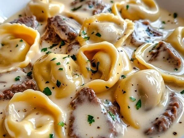 Cheesesteak tortellini in creamy provolone sauce served on a plate