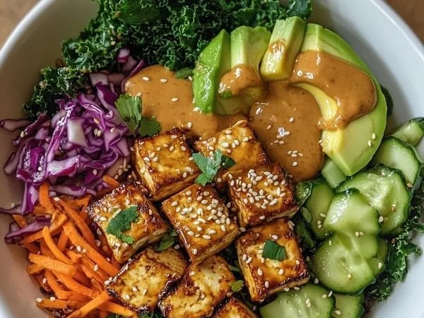 Buddha bowl featuring tofu drizzled with rich peanut sauce and fresh vegetables