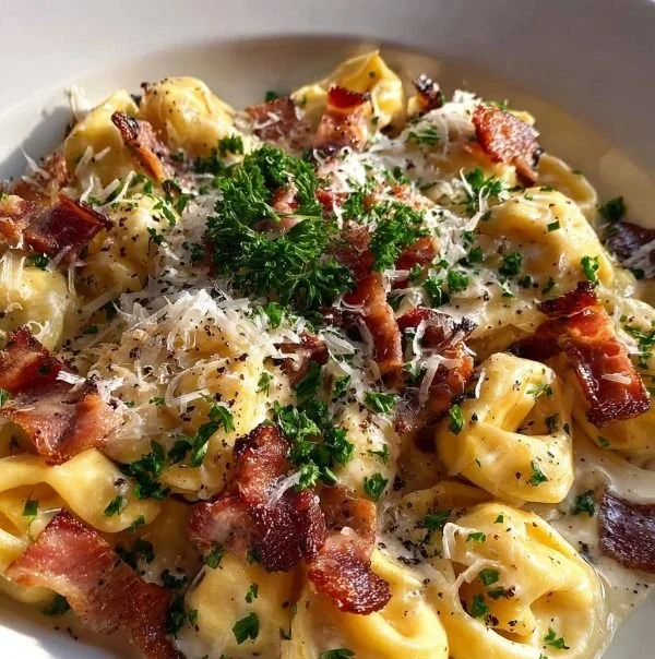 Silky tortellini served in creamy carbonara sauce, garnished with parmesan